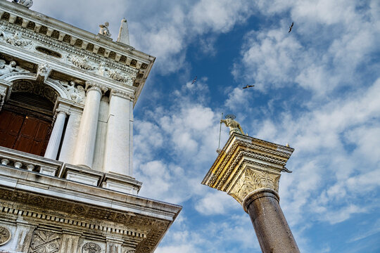 Close-up view of a top of a column of St Theodore (patron saint of Venice) and the Library of St. Mark facade. Saint Mark's Square. Venice, Italy.