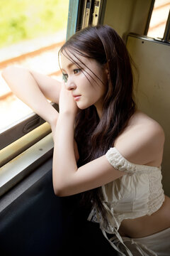 Social media trend in Thailand, Portrait of a stylish young Asian woman on a vintage train. Seated by the window, soft natural light creates a beautiful and timeless aesthetic.