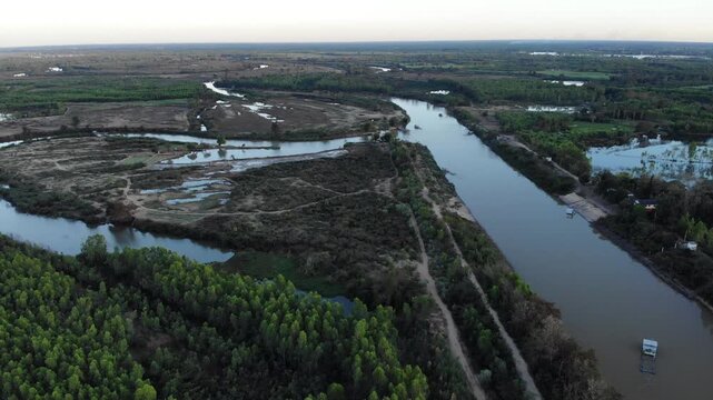 Aerial view of tropical river delta at sunset. Sunlight reflects in calm waters of river. Green forest and trees surround the watercourse at beautiful evening.