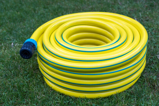 Unwrapped Yellow Garden Hose Coiled on Grass