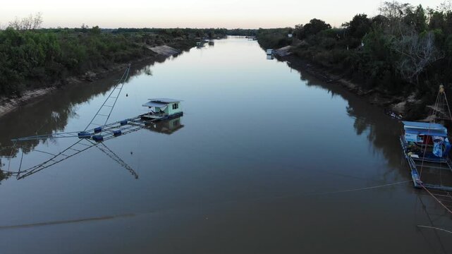 Aerial view of tropical river delta at sunset. Sunlight reflects in calm waters of river. Green forest and trees surround the watercourse at beautiful evening.