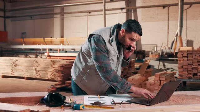 Phone call, laptop and carpenter with document in warehouse for timber order, stock or production. Tech, man and conversation with carpentry paperwork for woodwork manufacturing, inventory or supply