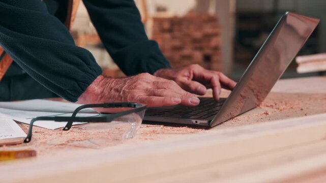 Person, hands or typing with laptop for carpentry project, lumber production or furniture business. Carpenter, computer and communication with technology for timber development or woodwork in factory