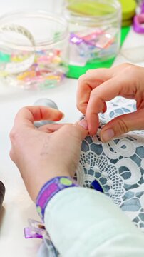 Seamstress hand sewing lace on denim fabric