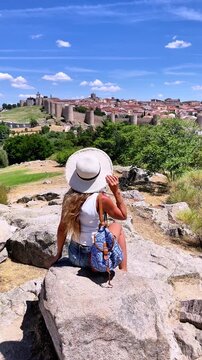 Woman Tourist with Hat Looking at Avila Medieval City Wall Spain Summer Travel Back View. Tour tourism in Spain, Castilla y Le&oacute;n
