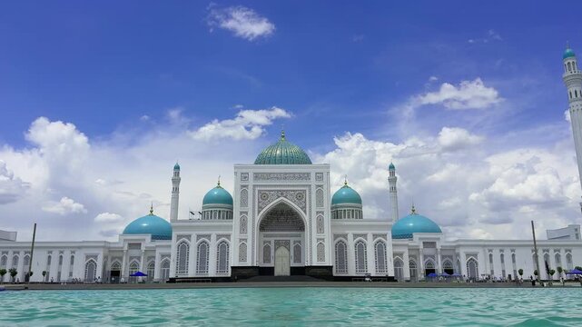 Front view of the Imam Al-Bukhari Mausoleum in Samarkand, Uzbekistan, reflected by a turquoise water with dramatic clouds. Famous Islamic landmark, pilgrimage destination, and masterpiece of Central