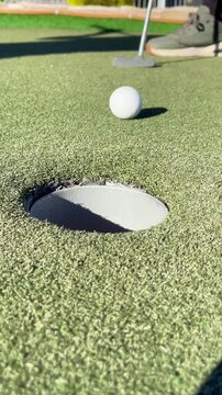 Mini Golf Ball Rolling into Hole Close Up Miniature Golfing Leisure Activity Putting Green