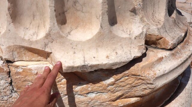 Tourist hand touching an ancient greek column
