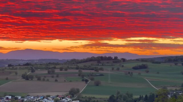 The clouds are dyed blood red by the setting sun, and the mountains in the background provide a striking contrast, panning shot