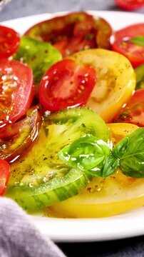 Fresh Heirloom Tomato Salad with Basil and pouring Olive Oil Organic Colorful Tomatoes Macro