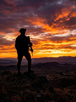 Silhouette of a soldier standing on a hill at sunset, holding a rifle, with a dramatic sky.