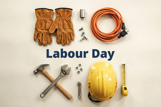 Labour Day greeting with industrial work tools, yellow hard hat and leather gloves on beige background, construction equipment for worker holiday