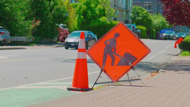 Orange road work construction sign and cone on city street
