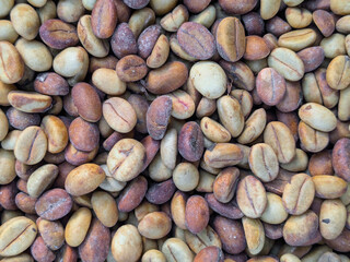 Obraz premium Raw, unroasted coffee beans, showing a mix of green, yellow, and light brown colors, in a dense texture overhead shot. A natural agricultural product.