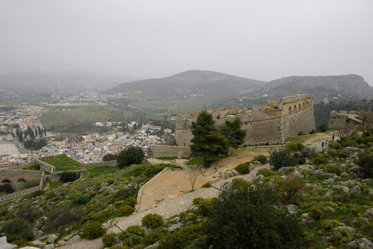 A panoramic view of the Acrocorinth fortress overlooking the city of Corinth in Greece on a hazy day.