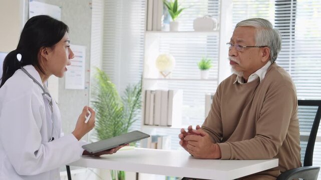 Doctor Reviewing Medical File While Interviewing Elderly Patient at Clinic or Hospital