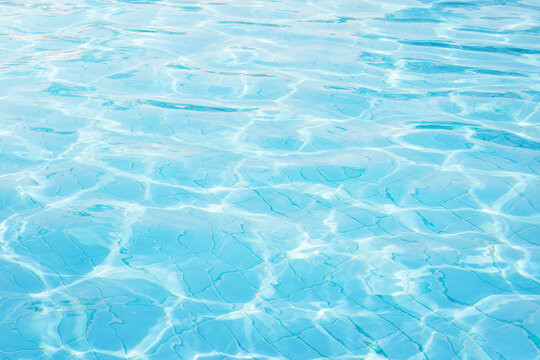 Blue aqua swimming pool surface with soft waves, sparkling light patterns and clear turquoise water, perfect for summer leisure, resort travel, wellness, relaxation, spa wellness mood, fresh lifestyle
