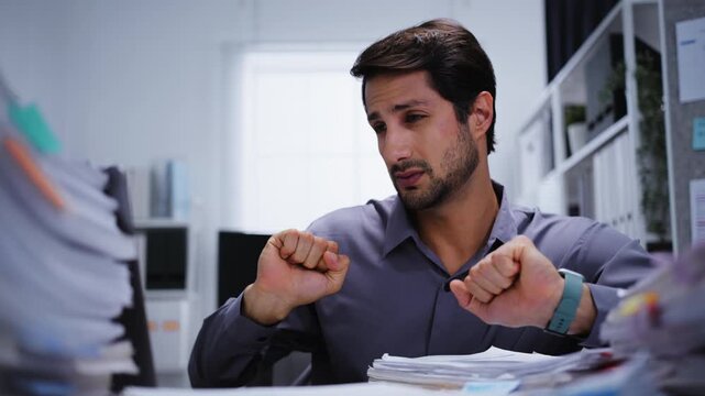 A tired businessman sleeps on paperwork at his desk during a late-night workload after becoming overworked and exhausted.