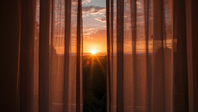 Closing curtains at sunset, calm mood