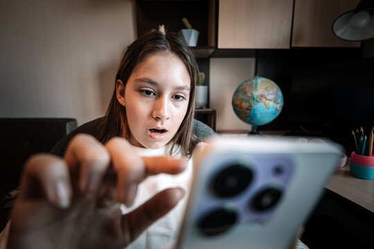 Young girl scrolling social media and watching short videos on smartphone. Surprised reaction while viewing reels and news feed.