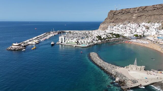 Aerial panorama flight towards Puerto de Mogan with beach, white houses, canal and marina at Atlantic ocean on Canary Island Gran Canaria, Spain
