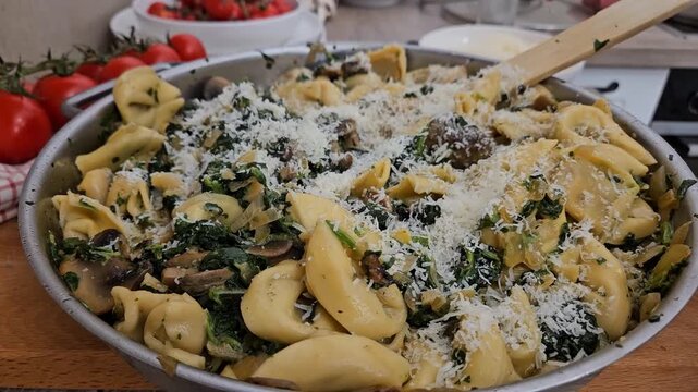 Chef hands sprinkling freshly grated parmesan cheese on a creamy tortellini pasta dish