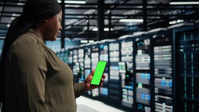 Engineer uses green screen tablet in a data center for system stability, network monitoring, infrastructure upgrades and steady IT infrastructure control within a practical data center workflow.