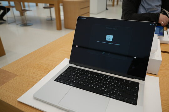 A new laptop shows the activation screen on a wooden table in a technology store.