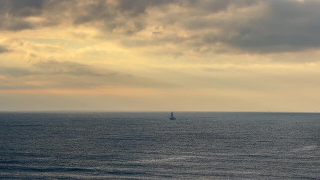 Static shot capturing the serene beauty of Virginia Beach's seascape featuring a distant sailboat during golden hour. Perfect for travel, seascape, sailing, corporate metaphor, or nature projects.