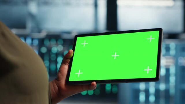 Admin uses green screen laptop and tablet in a data center for equipment checkups, infrastructure maintenance, software updates and steady IT infrastructure control.