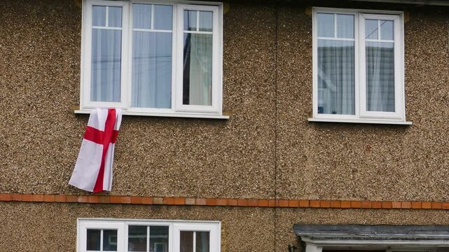 English St George's cross flags hanging from the windows of a typical residential council block. A symbol of patriotism and football support