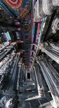 Intricately carved stone columns and polychrome ceiling inside an ancient temple for travel publishing, architectural heritage study and religious tourism background