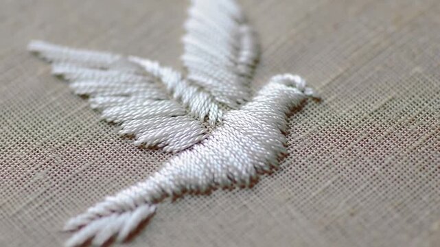 Close-up of white dove embroidery on textured fabric, symbolizing peace and hope
