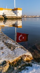 Fototapeta premium Calm water reflection of a red national flag by stone harbor steps at dusk for travel editorial, cultural storytelling and tourism marketing backgrounds