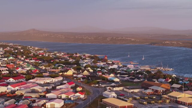 Aerial drone footage of Stanley town, harbor and colorful buildings along the coast in the Falkland Islands.