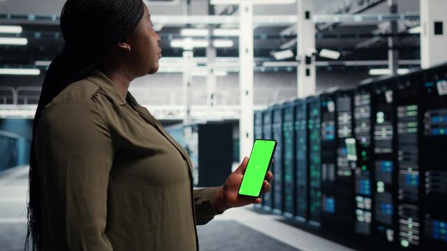 Programmer uses green screen laptop and tablet in a data center for equipment checkups, infrastructure maintenance, disaster recovery and steady IT infrastructure control.