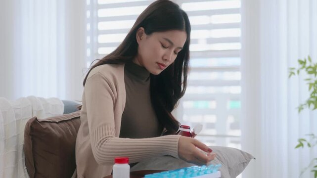 Asian woman organizing pills in a pill box for preparing daily routine medication
