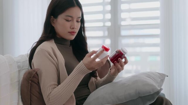 Asian woman checking on medicine bottle at home