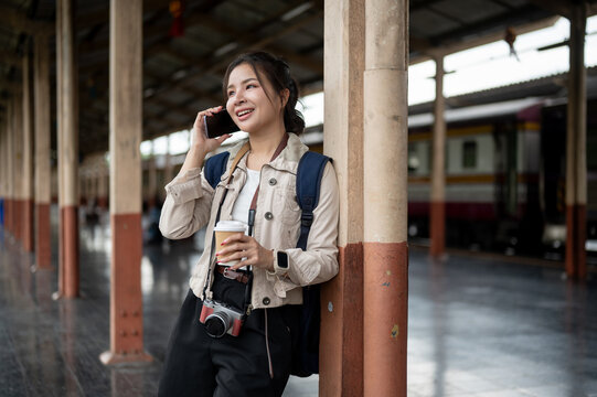 Asian woman talking on phone at train station.