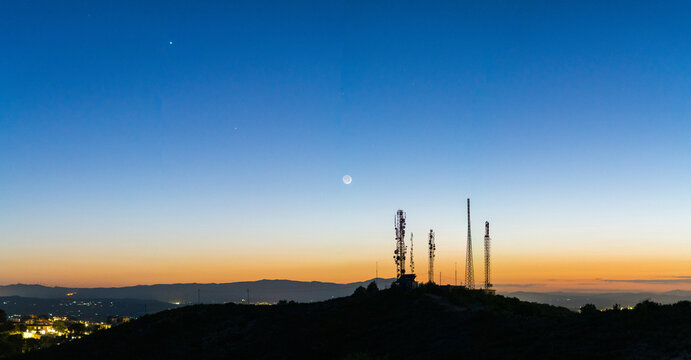 Moon, Jupiter, and Venus alignment above satellite towers at night