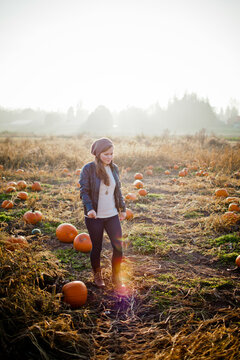 Young woman walking through a pumpkin patch field