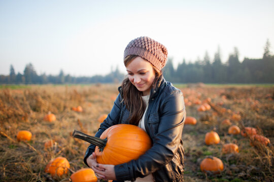 Young stylish woman in a beanie in a sunny pumpkin patch