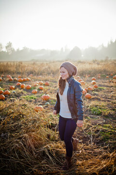 Young woman walks through a pumpkin patch field