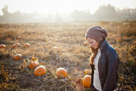 Young woman looking down thoughtfully in a pumpkin patch
