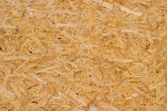 Close-up view of oriented strand board (OSB) texture showcasing wood strands and fibers layered together in a natural, light brown color suitable for construction and design applications