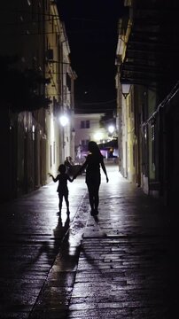 Mother and child silhouette walk down the street 