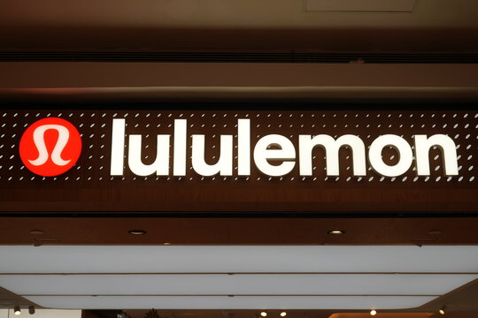 An illuminated lululemon store sign glows at a shopping center entrance.