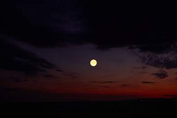 Fototapeta premium Full Moon on a twilight sky with landscape silhouettes.