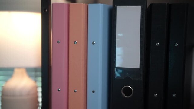 Professional office video showing organized binders and archived business files on a storage shelf. Ideal for concepts of corporate administration, document organization, office workflow, compliance, 