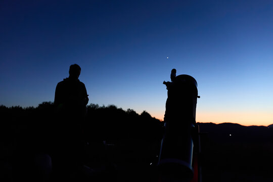 Amateur astronomer observing stars, planets, Moon and other celestial objects with a telescope in nature.